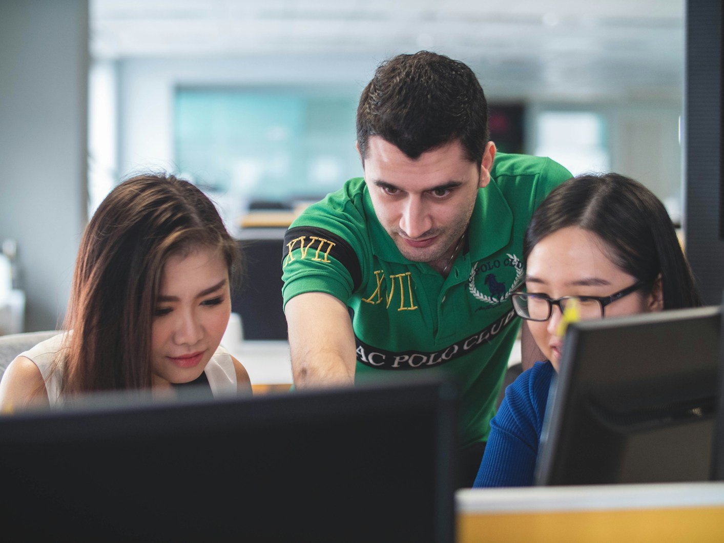 two women with teacher looking at computer screen